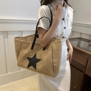 Woven straw tote bag with black leather star detail and long shoulder straps