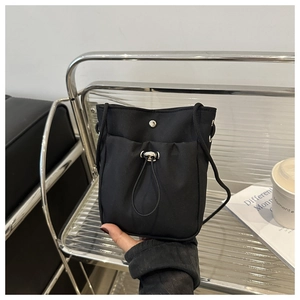 Detail van minimalistische zwarte nylon crossbodytas met zilveren verstelbare trekkoordgesp