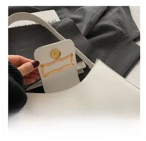 Close-up of golden metal magnetic buckle and premium hardware on white shoulder bag