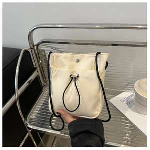 Detail van gebroken witte mini nylon crossbodytas met zwart trekkoord en zilveren gesp