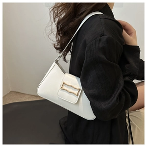 Close-up of a white minimalist underarm bag with gold metal buckle on a shoulder strap