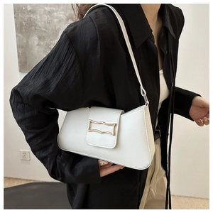 Detail of white leather baguette bag with golden wavy buckle on a black shirt