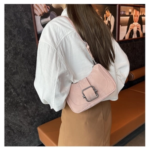 Pale pink leather shoulder bag with a large silver buckle shown in a cafe setting