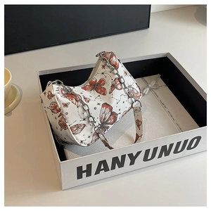 Detailed view of butterfly print underarm bag with silver chain in a premium gift box