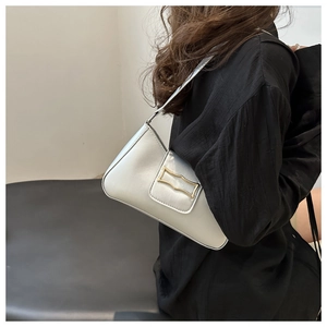 Detail of silver gray underarm bag with gold geometric buckle worn over a black shirt