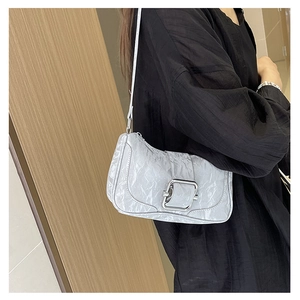 Detail of silver pleated shoulder bag featuring a large metallic buckle closure