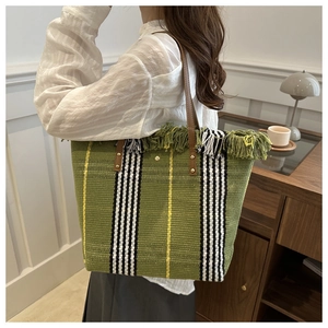 Detail of green woven canvas tote bag with yellow accents and stylish fringe trim