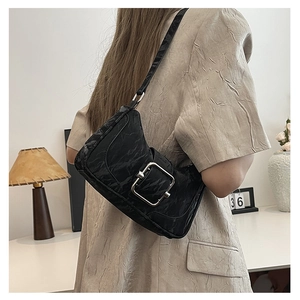 Close-up of black pleated shoulder bag featuring a vintage silver square buckle on the strap