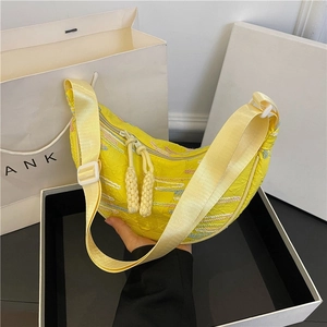 Yellow half-moon shoulder bag with wavy embroidery and woven tassels on a white background