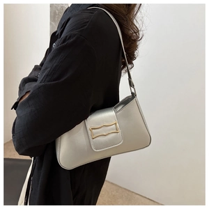 Side view of silver metallic underarm bag with golden wavy buckle on a model