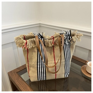 Detail of woven tote bag featuring fringe trim, iconic stripes and leather handles