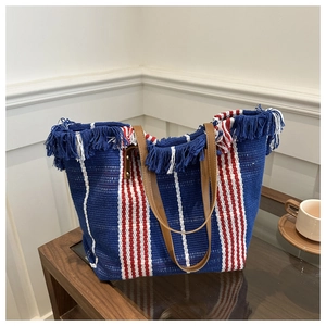 Detailed close-up of woven canvas tote with colorful stripes and decorative fringe