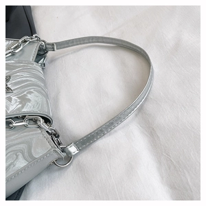 Nahaufnahme der silbernen Schultertasche mit Wellenfalten und dekorativer Metallkette