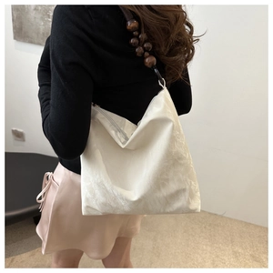 Close-up of white tote bag with silk gloss texture and dark brown wooden bead strap