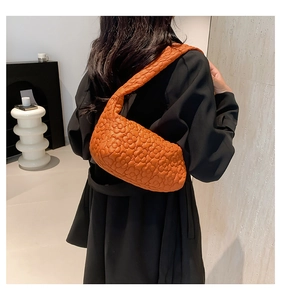 Sac à bandoulière matelassé orange avec texture florale porté par un mannequin