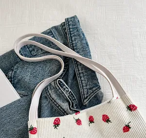 Detailopname van corduroy draagtas met aardbeienprint, materiaal en handgreep