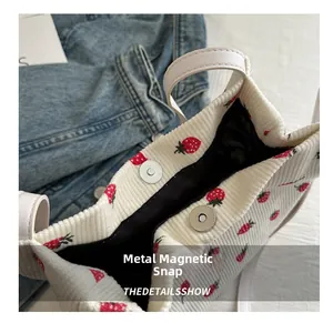Detailansicht des Metall-Magnetverschlusses an einer Cord-Tasche mit Erdbeermuster