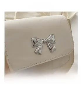 Close-up of cream white flap bag featuring a silver butterfly buckle and fine stitching