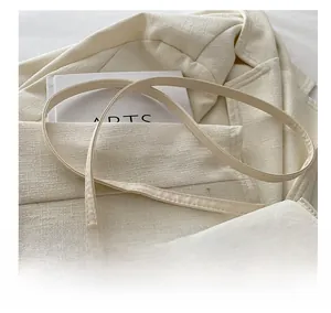 Detail of creamy white crossbody bag with silver bow clasp and thin leather shoulder strap