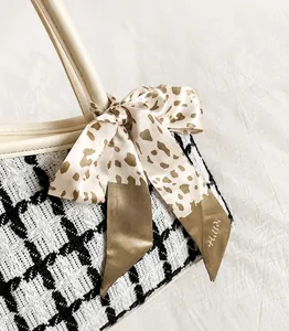 Detail van zwart-witte tweed shopper met beige leren handvat en sjaal met luipaardprint