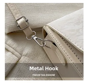 Close-up of premium metal hardware hook and adjustable strap on cream crossbody bag
