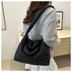 Close-up of black quilted puffer tote bag showing padded strap and soft texture