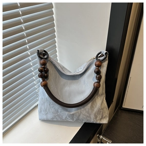 Detail of light blue pleated tote with artistic wooden bead handles and woven rope accents