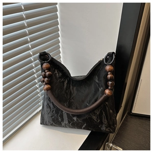 Detail of black pleated tote bag featuring vintage brown wooden bead handle on window sill