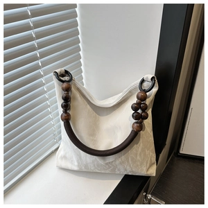 Detail of white pleated tote bag featuring unique wooden bead handles and woven rope accents