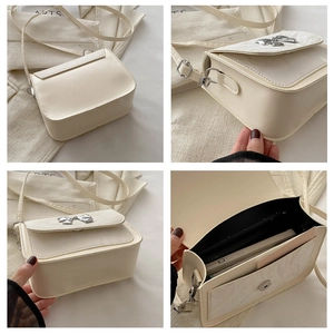 Detail view of cream crossbody bag featuring silver bow buckle and internal storage