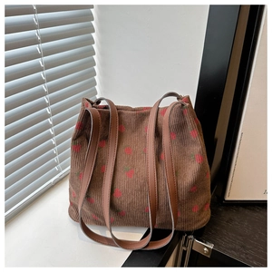 Detailansicht der braunen Cord-Tasche mit Erdbeerdruck auf einer sonnigen Fensterbank