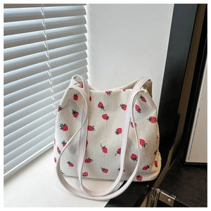 Detail der weißen Cord-Beuteltasche mit Erdbeermuster und weißen Schultergurten