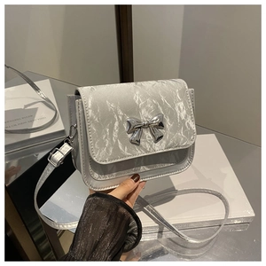 Close-up of silver square bag with metallic bow and crinkled texture leather finish