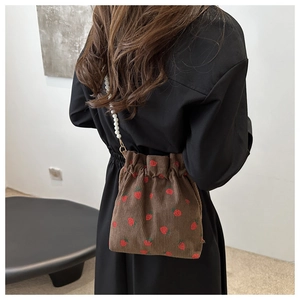 Détail du sac seau en velours côtelé avec imprimés fraises et anse en perles chic