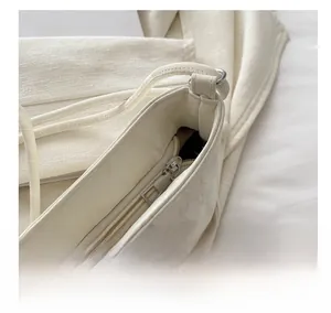 Close-up of smooth zipper closure and neat stitching on a cream white crossbody bag