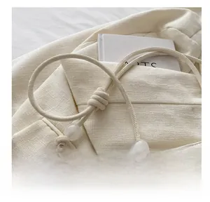Close-up of minimalist cream white shoulder bag with knotted leather strap and beads