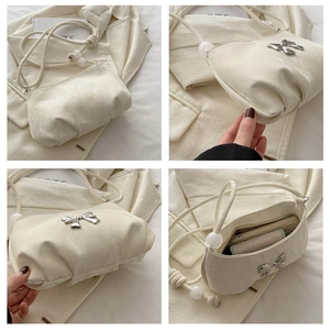 Detail of cream pleated crossbody bag with silver butterfly buckle and bead shoulder strap