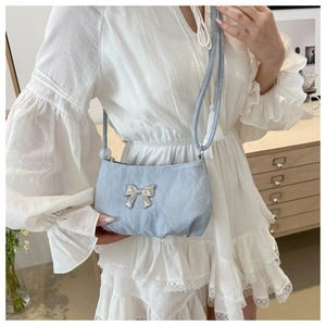 Close-up of light blue mini bag with silver bow detail and knotted shoulder strap