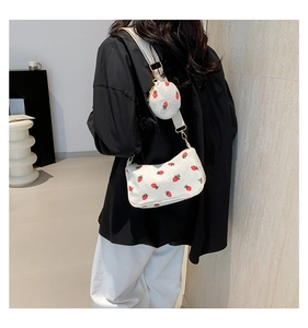 Detail of strawberry print corduroy crescent bag with adjustable wide strap and gold buckle
