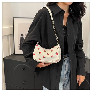 Detailansicht der weißen Cord-Baguette-Tasche mit Erdbeerdruck und goldener Kette
