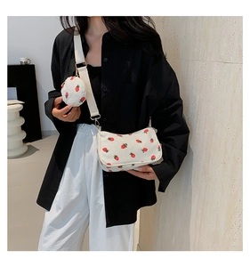 Detalle del bolso de pana blanca con estampado de fresas y un pequeño monedero