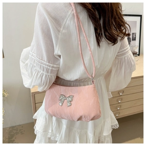 Close-up of pink shoulder bag with silver butterfly buckle on white dress model