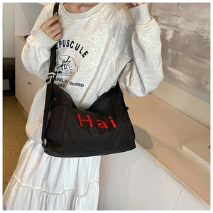 Close-up of black nylon tote bag featuring red Hai embroidery and wide adjustable strap