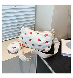 Detail view of white corduroy shoulder bag set with strawberry prints and a coin purse