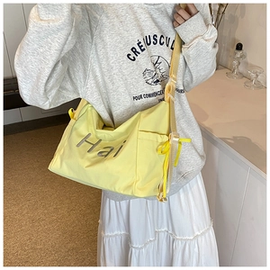 Large yellow canvas tote bag featured with side pocket and ribbon on a female model