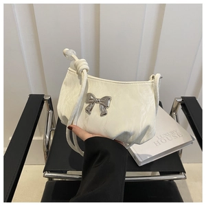 Close-up of beige ruched bag with silver butterfly buckle and beaded strap detail