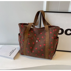 Gros plan du sac cabas en velours côtelé marron avec broderie fraise et bouton pression