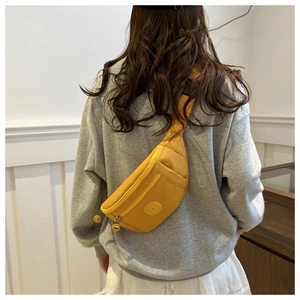 Détail d'un sac banane de sport en nylon jaune avec fermeture éclair porté par un mannequin