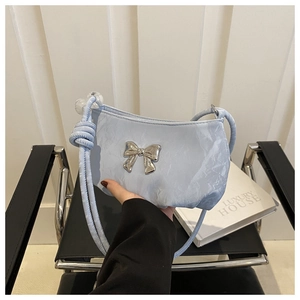 Detail of light blue pleated handbag featuring a silver metal bow and beaded strap