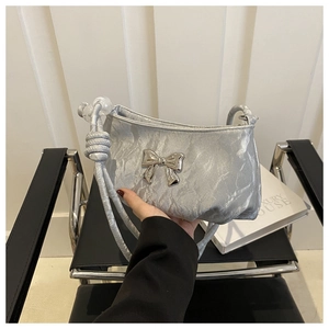 Detail of silver pleated texture shoulder bag with metallic butterfly buckle and beaded strap